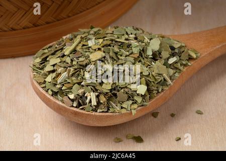 Holzlöffel mit getrockneten traditionellen südamerikanischen koffeinreichen Mate-Teeblättern aus nächster Nähe Stockfoto