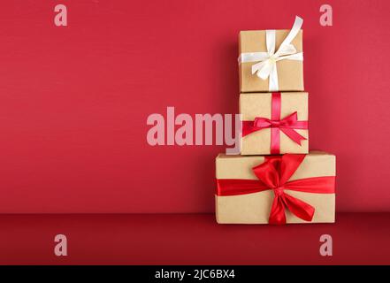 Geschenkschachteln auf rotem Hintergrund. Weihnachtsgeschenke. Paketzustellung. Stockfoto