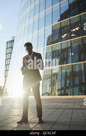 Stilvoller, hübscher, junger, schwarzer Geschäftsmann mit Brille, Smartphone und Kaffee unterwegs Stockfoto