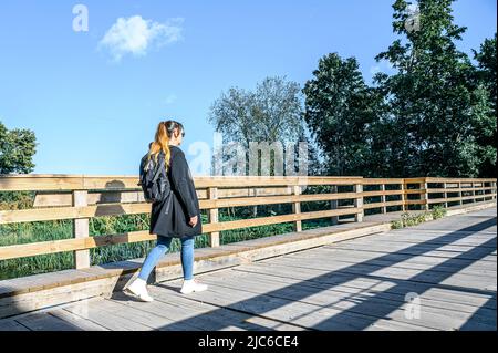 Eine Frau geht auf einer Holzbrücke über den Fluss. Reisen vor Ort. Stockfoto