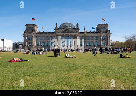 16.04.2022, Berlin, Deutschland, Europa - Menschen auf dem Rasen vor dem Reichstagsgebäude im Bezirk Mitte am Platz der Republik. Stockfoto