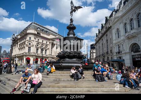 London, Großbritannien. 10. Juni 2022. Auf den Stufen des Eros im Piccadilly Circus sitzen Menschen. Das Office of National Statistics (ONS) hat berichtet, dass fast 990.000 Menschen in Großbritannien in der vergangenen Woche einen positiven Covid-19-Test durchgeführt haben, gegenüber 954.000 in der Vorwoche. Die positiven Fälle sind zum ersten Mal seit Ende März Woche für Woche gestiegen, und die ONS haben gesagt, dass es sich bei den Fällen wahrscheinlich um die BA.1-Omicron-Variante und neuere BA.4- und BA.5-Varianten handelt. Kredit: Stephen Chung / Alamy Live Nachrichten Stockfoto
