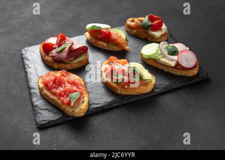 Bruschetta vor dunklem Hintergrund. Italienische Vorspeise auf Schiefer Stockfoto