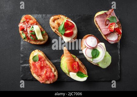 Bruschetta italienische Vorspeise, die traditionell vor den Hauptgerichten serviert wird. Italienische Vorspeise auf dunklem Hintergrund. Brushetta Stockfoto