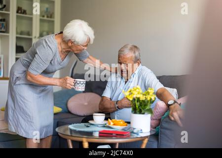 Besorgte ältere Frau, die ihren Mann tröstet, der Schmerzen hat Stockfoto