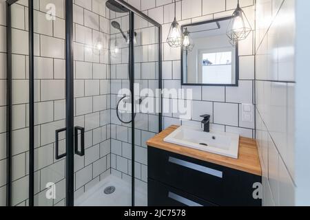 Modernes Badezimmer mit Waschbecken und Duschkabine. Weiße Fliesen an den Wänden Stockfoto