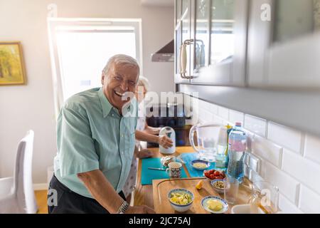 Ein Seniorenpaar in einer Küche, das Frühstück zubereitet Stockfoto