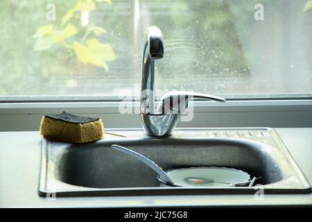 Schmutziges Geschirr im Waschbecken auf dem Tisch in der Küche unter fließendem Wasser, schmutziges Geschirr im Mokka in der Küche zu Hause Stockfoto