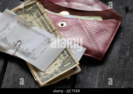Ein Scheck aus dem Supermarkt mit Dollars liegt ein Husten mit Geld auf einem Holztisch im Licht zu Hause, Geld auf dem Tisch, finanzieren Stockfoto
