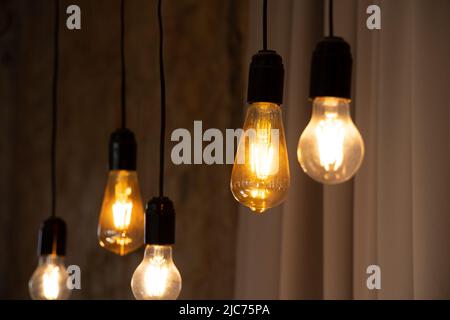 Lampen im Retro-Stil hängen in der Nähe der alten Backsteinmauer in Stimmung, Retro-Beleuchtung, Inneneinrichtung, Retro-Glühbirne Stockfoto