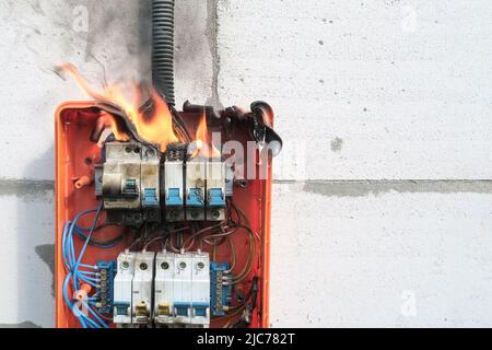 Brennende Schalttafel durch Überlast oder Kurzschluss an der Wand Stockfoto