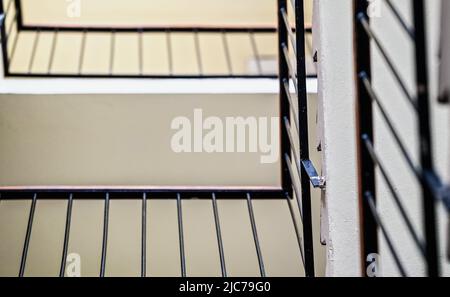 Blick auf Wendeltreppe in Wohnblock Gebäude, Metallzaun und Betonboden schaffen abstrakte Muster Stockfoto