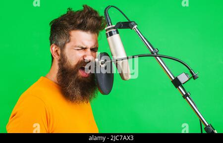 Professioneller Sänger singt im Kondensatormikrofon. Konzept der Musikproduktion. Bärtiger Mann, der singt. Stockfoto