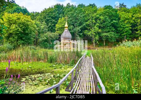 Gehen Sie die alte Holzbrücke über den Fluss zum Wald im kleinen Dorf Tscherevki, Ukraine Stockfoto