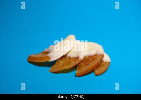 Trockene Orangen in weiße Schokolade getaucht mit blauem Hintergrund isoliert Stockfoto
