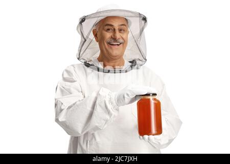 Bienenhalter in einer Uniform, der ein Honigglas auf weißem Hintergrund isoliert hält Stockfoto