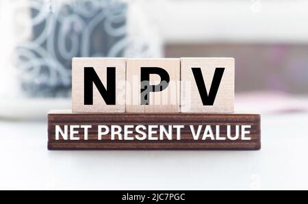 Net present value. NPV the word on wooden cubes, cubes stand on a reflective surface, in the background is a business diagram. Business and finance co Stockfoto