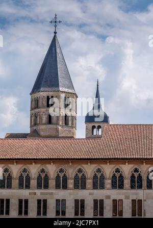 Blick auf eine Reihe gotischer Bogenfenster und einen romanischen Kirchturm mit spitzem Dach im ehemaligen Benediktinerkloster von Cluny France Stockfoto