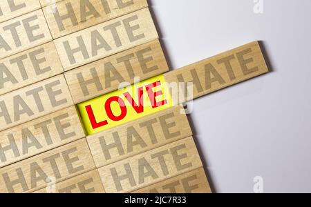 Stehende hölzerne Buchstabenkacheln bilden Wörter auf einer grauen gusseisernen Oberfläche im Hintergrund, Liebe, Hass. Stockfoto