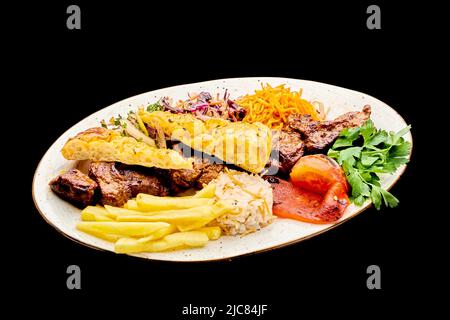 Der saftige Rinderkebab wird auf einem Teller mit Pommes Frites auf einem schwarzen, isolierten Hintergrund angelegt Stockfoto