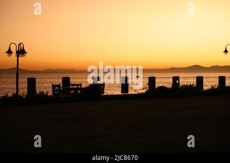 Blick auf den Sonnenuntergang von Kapstadt, VA Waterfront, Houts Bay, gelber Himmel und Küstenspaziergang Stockfoto
