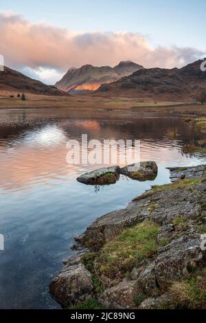 Epische Landschaft mit Sonnenaufgangslicht über Blea Tarn im Lake District mit atemberaubendem Licht auf fernen Bergen Stockfoto