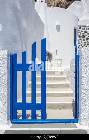 Eingang zu einem traditionellen griechischen Haus im Inselstil mit blauem Tor und weiß getünchten Stufen und Wänden. Aufgenommen auf der Insel Santorini, Griechenland. Vertica Stockfoto