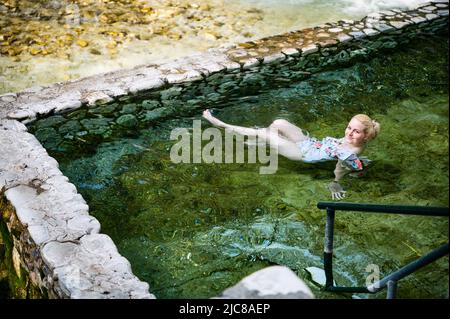 Blonde Frau im Badeanzug Baden in den heißen Quellen von Loutra Pozar Stockfoto