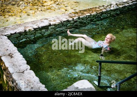 Blonde Frau im Badeanzug Baden in den heißen Quellen von Loutra Pozar Stockfoto