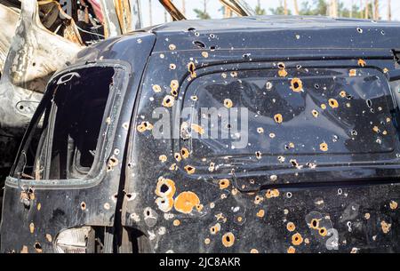 Geschossene, beschädigte Autos während des Krieges in der Ukraine. Das Fahrzeug von Zivilisten, die von den Händen des russischen Militärs betroffen sind. Schrapnel und Einschusslöcher in der Stockfoto