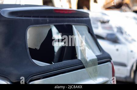 Beschädigtes Dachmaterial auf der Rückseite des Cabrios. Vandalismus, Diebe schneiden das Dach eines Cabrios von hinten. Diebstahl von Dingen aus dem Auto. Krim Stockfoto