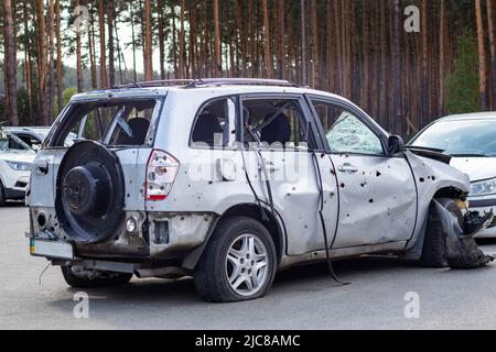 Geschossene, beschädigte Autos während des Krieges in der Ukraine. Das Fahrzeug von Zivilisten, die von den Händen des russischen Militärs betroffen sind. Schrapnel und Einschusslöcher in der Stockfoto