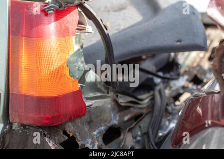 Eine rote und orangefarbene Glaslampe an einem Auto als Folge eines heftigen Zusammenstoßes. Defekte Heckscheinwerfer in Nahaufnahme aufgrund eines Autounfalls oder fahrlässigen Drivi Stockfoto