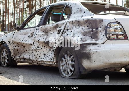 Geschossene, beschädigte Autos während des Krieges in der Ukraine. Das Fahrzeug von Zivilisten, die von den Händen des russischen Militärs betroffen sind. Schrapnel und Einschusslöcher in der Stockfoto