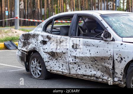 Geschossene, beschädigte Autos während des Krieges in der Ukraine. Das Fahrzeug von Zivilisten, die von den Händen des russischen Militärs betroffen sind. Schrapnel und Einschusslöcher in der Stockfoto