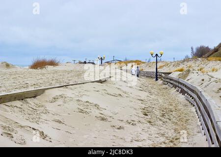 Sandboardwalk. Beleuchtung. Wanderfrauen. Bewegung der Dünen. Strand im Winter Stockfoto