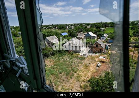 Saporischschschja, Ukraine. 10.. Juni 2022. REGION SAPORISCHSCHSCHJA, UKRAINE - 10. JUNI 2022 - Blick auf Privathäuser durch ein kaputtes Fenster einer vollständig zerstörten Wohnung in einem Wohngebäude, das durch russische Beschuss des Dorfes Komyschuvakha, Region Saporischschschja, im Südosten der Ukraine beschädigt wurde. Dieses Foto kann nicht in der russischen Föderation verteilt werden. Kredit: Ukrinform/Alamy Live Nachrichten Stockfoto