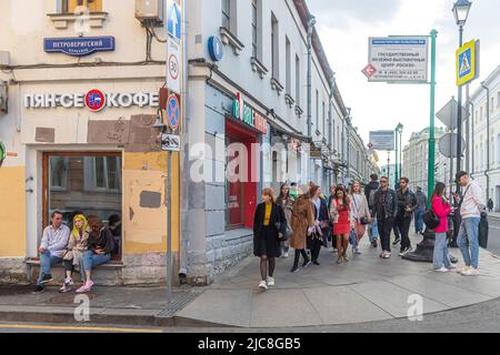 Moskau, Russland - am 22. Mai 2022 sitzen Ein Mann und zwei Mädchen auf dem Fensterbrett eines Straßencafés, eine Menschenmenge geht vorbei. Marosseyka Straße Stockfoto