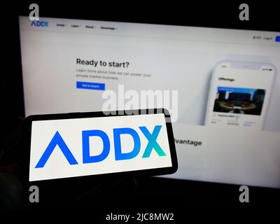 Person, die das Smartphone mit dem Logo der Fintech-Firma ICHX Tech Pte. Ltd. (ADDX) auf dem Bildschirm vor der Website hält. Konzentrieren Sie sich auf die Telefonanzeige. Stockfoto