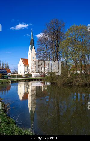 Ländliche Kirche im Dorf Waidhofen in Bayern. Spiegelung des Gebäudes in einem kleinen See. Stockfoto