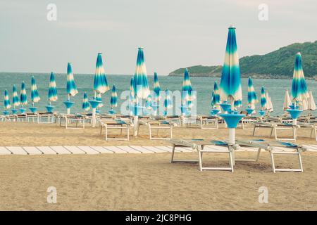 Sonnenschirme und Liegen für Entspannung und Komfort am Strand. Frohe Sommerferien und Resortkonzept. Bezahlter Service am Strand. Stockfoto
