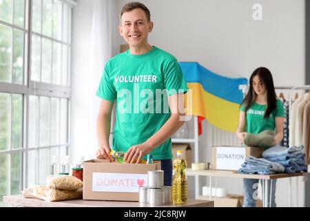 Polnischer Freiwilliger, der eine Flasche Sonnenblumenöl in eine Spendenbox für die Ukraine in der Mitte legt Stockfoto