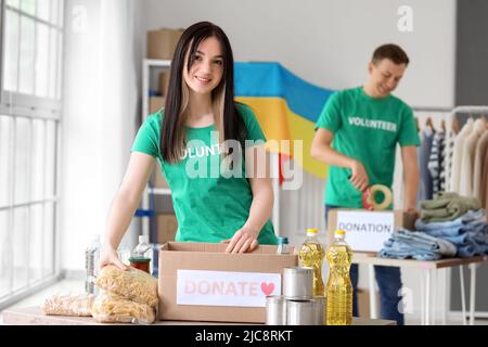 Polnischer Freiwilliger, der Lebensmittel in eine Spendenbox für die Ukraine in der Mitte einlegt Stockfoto