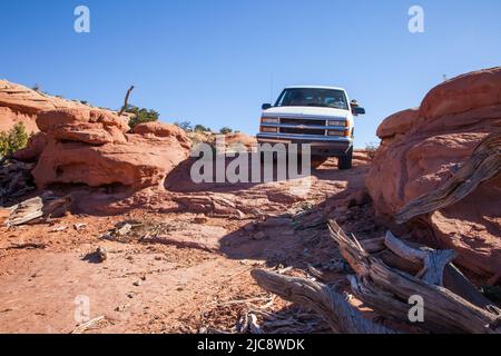 Ein Reiseleiter fährt einen SUV aus dem Jahr 4WD über einen rauhen Slickrock-Trail auf dem Navajo Indianerreservat in Arizona. Stockfoto