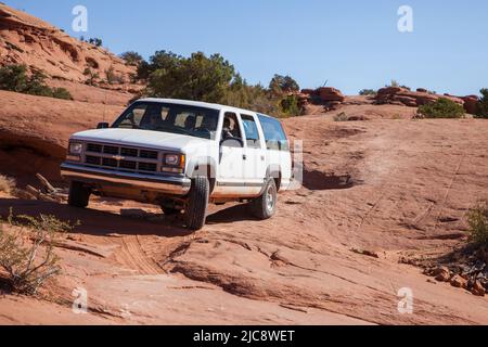 Ein Reiseleiter fährt einen SUV aus dem Jahr 4WD über einen Slickrock-Pfad auf dem Indianerreservat Navajo in Arizona. Stockfoto