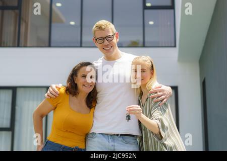 Kaukasisches Familienportrait mit Schlüsseln zu einem neuen Zuhause unterwegs am Tag. Stockfoto