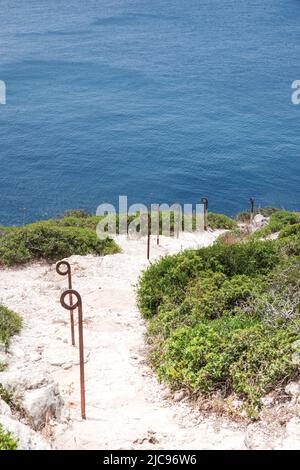 Felsiger Fußweg mit alten Eisenmarkierungen, der von der Festung Fortaleza do Beliche zum Ufer führt - Sagres, Algarve, Portugal Stockfoto