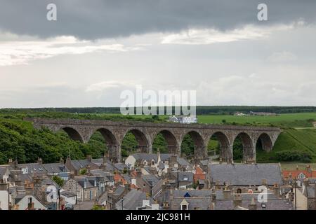 10. Juni 2022. Cullen, Moray, Schottland. Dies ist Blick über die Seatown Houses in Cullen in Richtung des alten Eisenbahnviadukts und des Cullen Bay Hotels als Regenclo Stockfoto