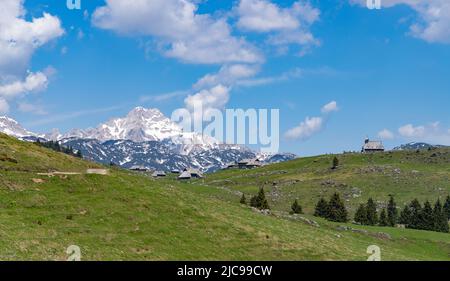 Ein Bild der Landschaft von Velika Planina, oder Big Weide Plateau, und seine Hirtenhütten, mit der Kapelle der Maria des Schnees auf der rechten Seite und der K Stockfoto