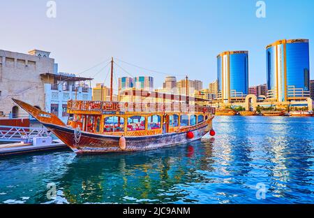 DUBAI, VAE - 1. MÄRZ 2020: Das alte hölzerne Dhow-Boot, das am Pier von Al Seef mit Blick auf den Dubai Creek und die Deira Twin Towers im Hintergrund festgemacht ist Stockfoto